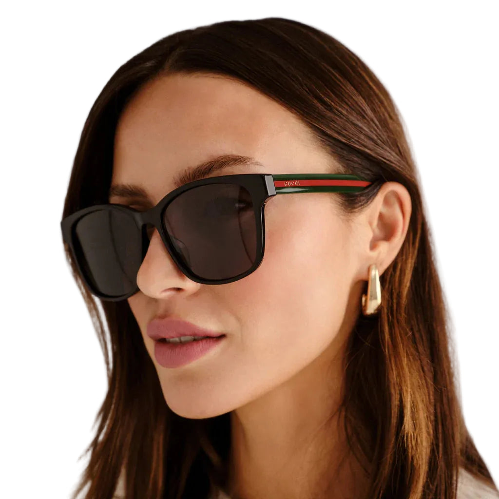Woman wearing dark sunglasses with a neutral background